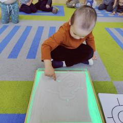 Chłopiec odtwarza wzór na tacce z piaskiem