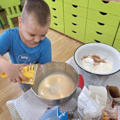 Chłopiec dodaje wiórki kokosowe do ciasta