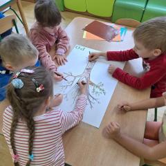 Dzieci kolorują pień drzewa