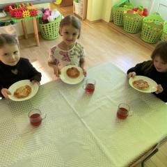 Dzieci siedzą przy stole i jedzą pizzę