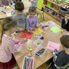 dzieci robią pracę plastyczną przy stoliku