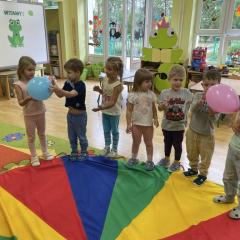 Dzieci podają sobie balony stojąc w kole