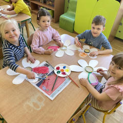 Dzieci przy stolikach wykonują pracę plastyczną