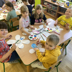 Dzieci przy stolikach wykonują pracę plastyczną