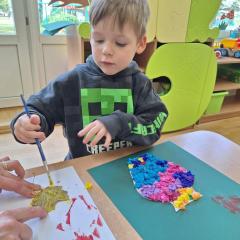 chłopiec maluje liście farbą