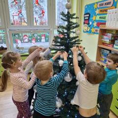 dzieci wspólnie ubierają choinkę
