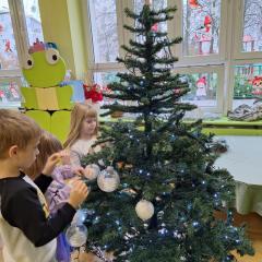 dzieci zakładają bombki na choinkę