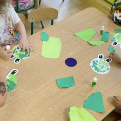 Dzieci przy stolikach wykonują pracę plastyczną