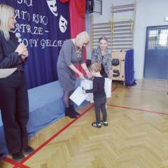 Chłopiec odbiera dyplom i nagrodę w konkursie recytatorskim