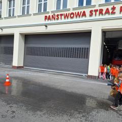 chłopiec próbuje strącić pachołek wodą z węża strażackiego
