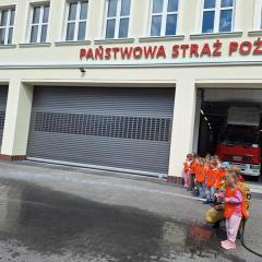 dziewczynka próbuje strącić pachołek wodą z węża strażackiego