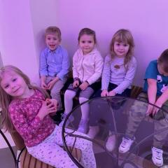 Dzieci siedzą przy stoliku i czekają na spektakl 