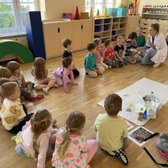 Dzieci obserwują eksperyment, prowadzącą pokazuje dzieciom miskę z bliska